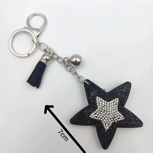 Schwarzer Stern-Schlüsselanhänger mit silbernem Strass, Quaste und Glocke auf weißem Hintergrund