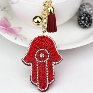 Hamsa Hand keychain with red rhinestones, golden bell and tassel on white cup