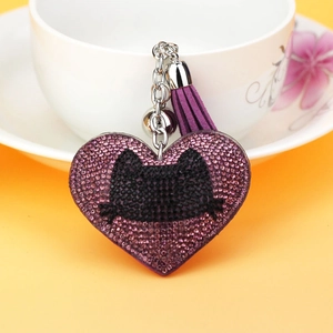 Close-up of heart-shaped keychain with purple rhinestones, black cat motif and tassel