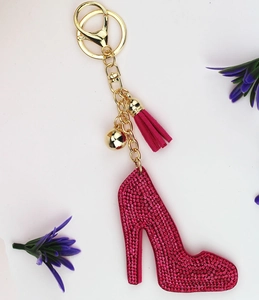 Detail of a pink rhinestone high heel keychain with a gold bell and a soft suede tassel