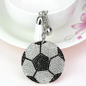 Détail du porte-clés football en strass avec pompon blanc et clochette sur tasse