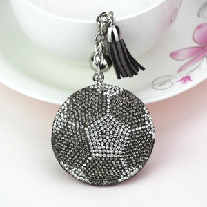 Détail macro d'un porte-clés de football étincelant avec des strass gris et un pompon doux