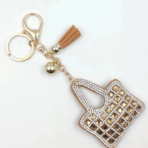 Detailed view of mini purse keychain with amber rhinestones and brown leather tassel