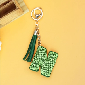 Sparkling green rhinestone letter N keychain with a stylish leather tassel on yellow backdrop