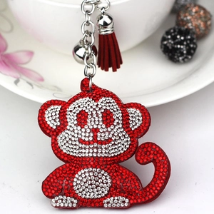 Macro shot of red rhinestone monkey keychain with silver bell and textile tassel charm
