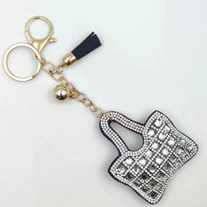 Detail of a mini handbag keychain with sparkling rhinestones, gold chain, and black tassel