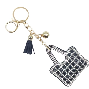 Mini handbag keychain with white crystals, black stones, and leather tassel on white background
