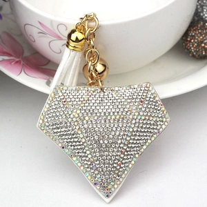 Glitzernder diamantförmiger Schlüsselanhänger mit weißer Quaste und Kristallen an einer Tasse
