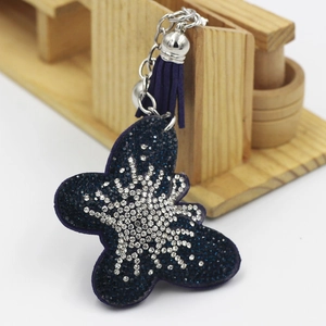 Vue détaillée porte-clés papillon en strass bleus avec pompon violet élégant