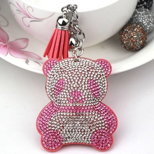 Close-up of bear keychain with pink rhinestones, leather tassel, and silver bell detail