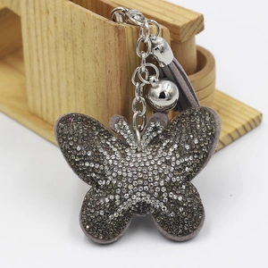 Détail du porte-clés papillon avec strass brillants et pompon à franges gris