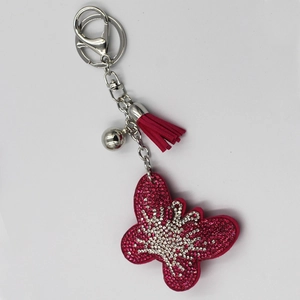 Vue détaillée du porte-clés papillon en strass avec pompon rose et fermoir argenté