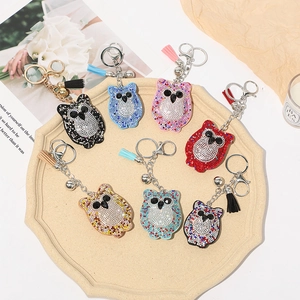 Détail de porte-clés hibou avec strass colorés et pompons assortis sur un plateau