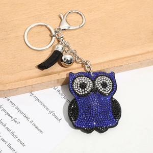 Porte-clés chouette avec strass bleus étincelants, clochette et pompon sur fond bois