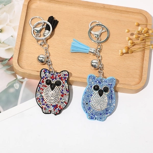Détail de porte-clés hibou en strass colorés avec glands sur un plateau en bois