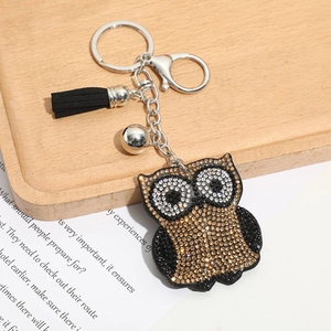 Détail d'un porte-clés hibou scintillant avec pompon noir et anneaux en métal argenté