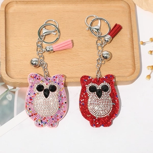 Gros plan sur les porte-clés hibou en strass avec pompons et clochettes sur un plateau