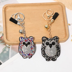Détail de porte-clés hibou avec strass colorés, pompons noirs et petites cloches