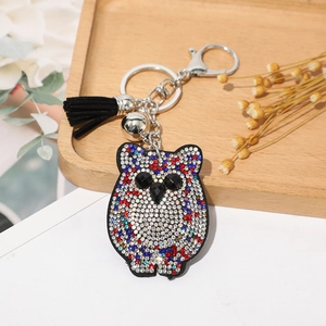 Détail du porte-clés hibou avec strass colorés, frange noire et petite cloche en métal argenté