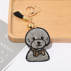 Gros plan du porte-clés chiot bichon strassé avec fermoir doré et élégant pompon noir
