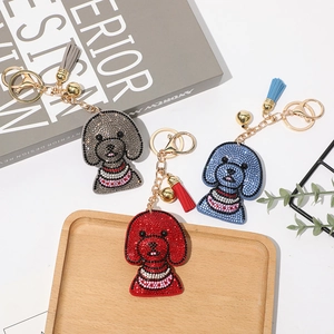 Vue détaillée de trois porte-clés chien en strass avec pompons et clochettes dorées