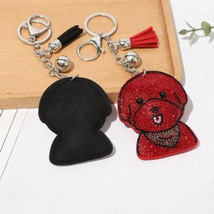 Détail d'un porte-clés caniche en strass avec pompons en soie et clochette sur bois
