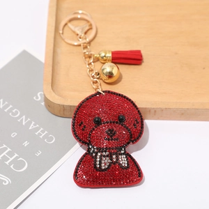 Détail macro du porte-clés chien en strass rouges avec grelots dorés et glands