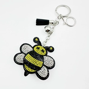Close-up of cute bee keychain with rhinestones, silver bell and black leather tassel
