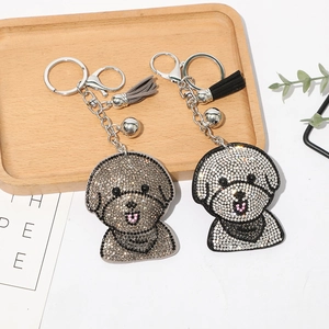 Détail d'un porte-clés chien en strass avec pompon en cuir et petite clochette