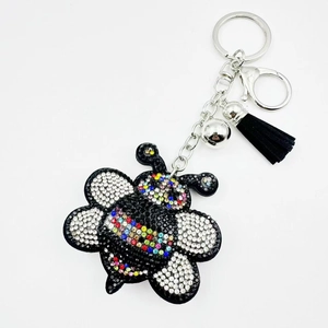 Detailed view of rhinestone bee keychain with silver metal clip and black tassel charm
