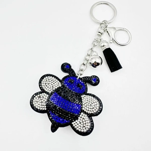 Detail of blue rhinestone bee keychain with black leather tassel and silver bell accessory