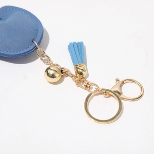 Détail du pendentif cœur bleu en daim avec pompon et anneau métallique doré chic