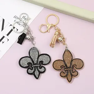Détail de porte-clés fleur de lys avec strass, pompons en cuir et petites cloches