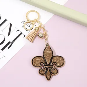 Détail d'un porte-clés fleur de lys avec strass étincelants et pompon beige doux