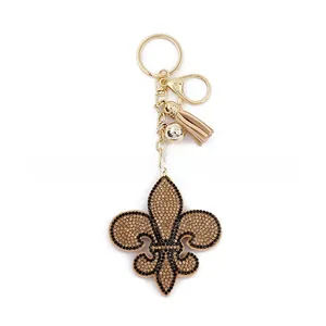 Détail d'un porte-clés fleur de lys avec strass dorés et pompon élégant en cuir beige