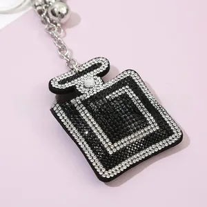 Macro shot of rhinestone perfume bottle keychain with silver chain on purple background