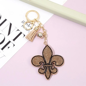 Porte-clés fleur de lys doré avec strass marron et un élégant pompon en cuir beige