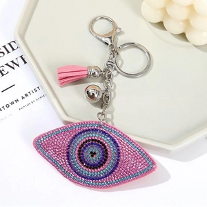 Dettaglio portachiavi malocchio con strass rosa e blu, nappa e un piccolo campanellino