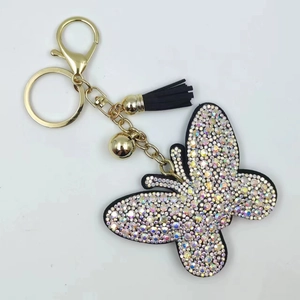 Macro detail of butterfly keychain with colorful rhinestones, gold hardware, and black tassel