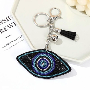 Portachiavi occhio blu scintillante con strass e nappa nera su vassoio decorativo