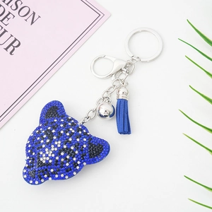 Détail du porte-clés tête de léopard avec cristaux bleu marine, pompon en cuir et clochette