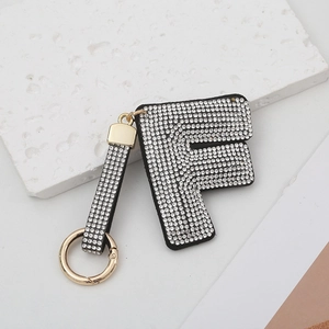 Porte-clés luxe lettre F orné de strass blancs avec anneau doré sur marbre