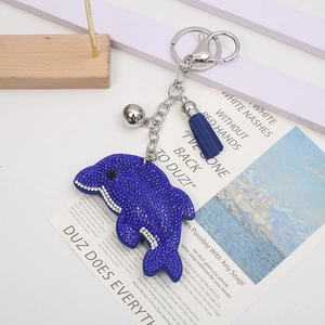 Vue détaillée d'un porte-clés dauphin en strass bleus avec pompon scintillant et clochette