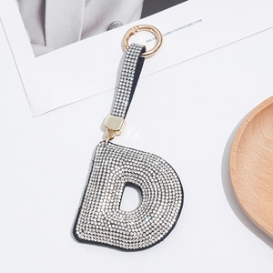 Sparkling crystal-encrusted letter D keychain with golden spring clasp on a stylish table