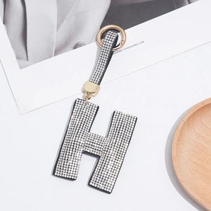 Macro shot of sparkling rhinestone letter H keychain with gold ring and crystal strap