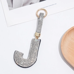 Close-up of golden letter J keychain accessory with sparkling clear rhinestones