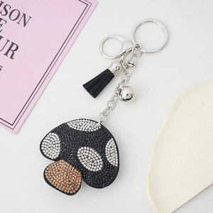 Detail of mushroom keychain with white and brown rhinestones, black tassel and silver bell
