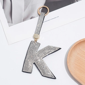 Macro shot of silver letter K keychain with rhinestones on a white background