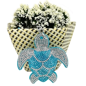 Sparkling blue crystal turtle keychain with rhinestone shell hanging on white floral background