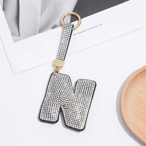 Macro detail of gold-plated letter N keychain with sparkling white rhinestones
